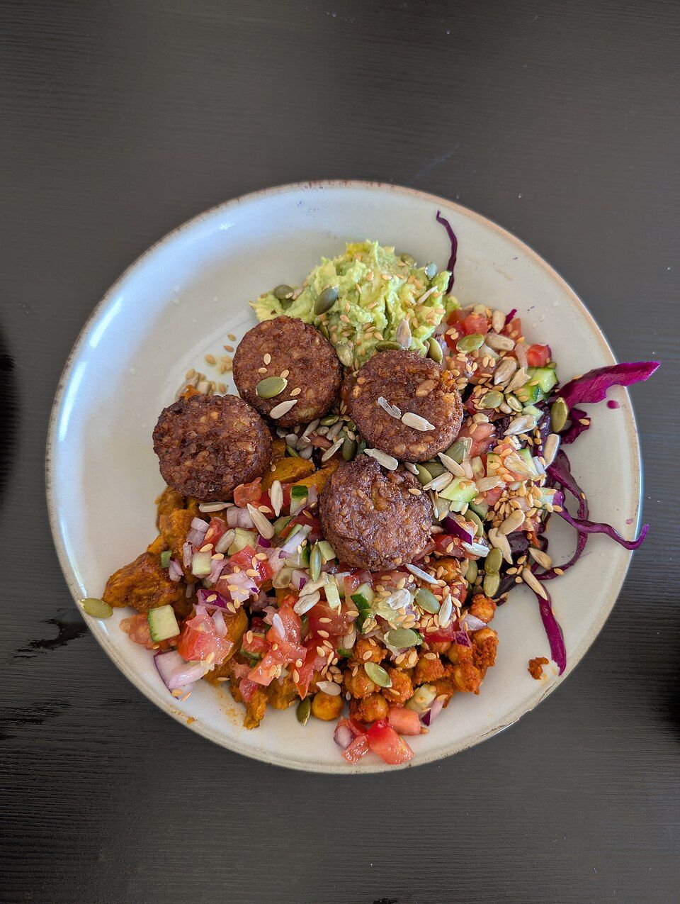 A colourful buddha bowl with falafel, grains and seeds