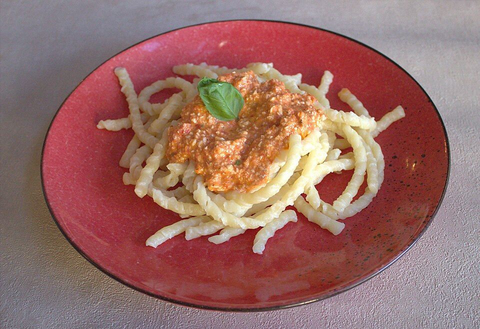 Pasta tossed in a creamy pesto sauce on a red plate